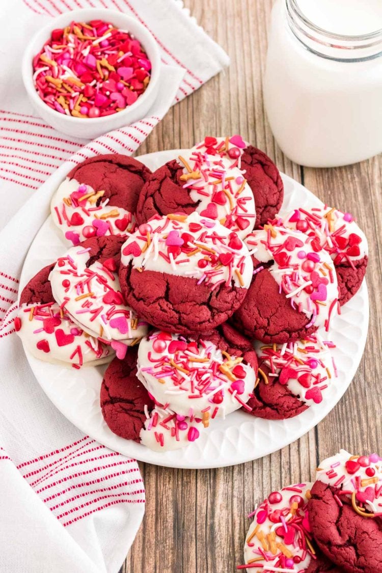 Valentine's Day decorated red velvet cookies on a white plate on a wooden counter.