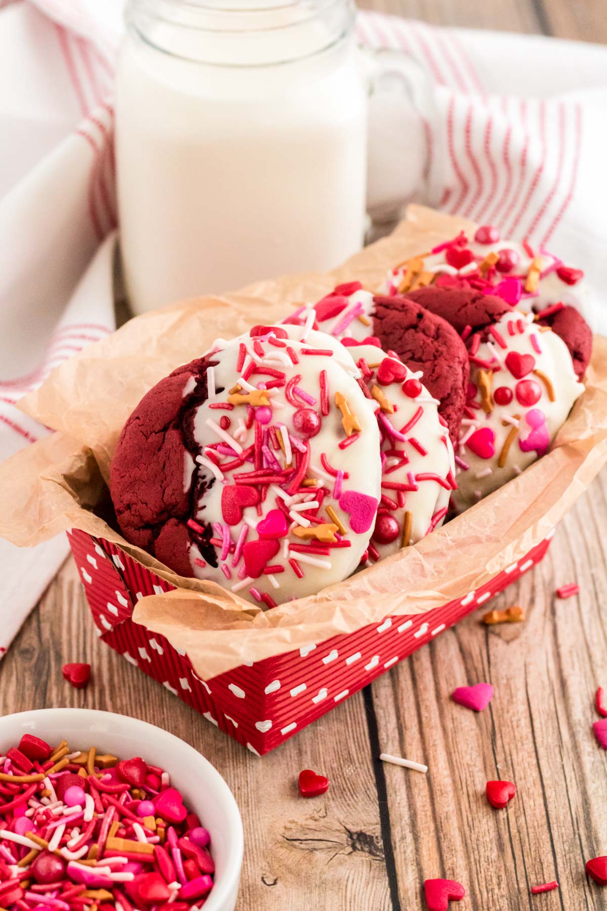 Red Velvet cookies dipped in white chocolate and topped with sprinkles in a Valentine's Day treat box.