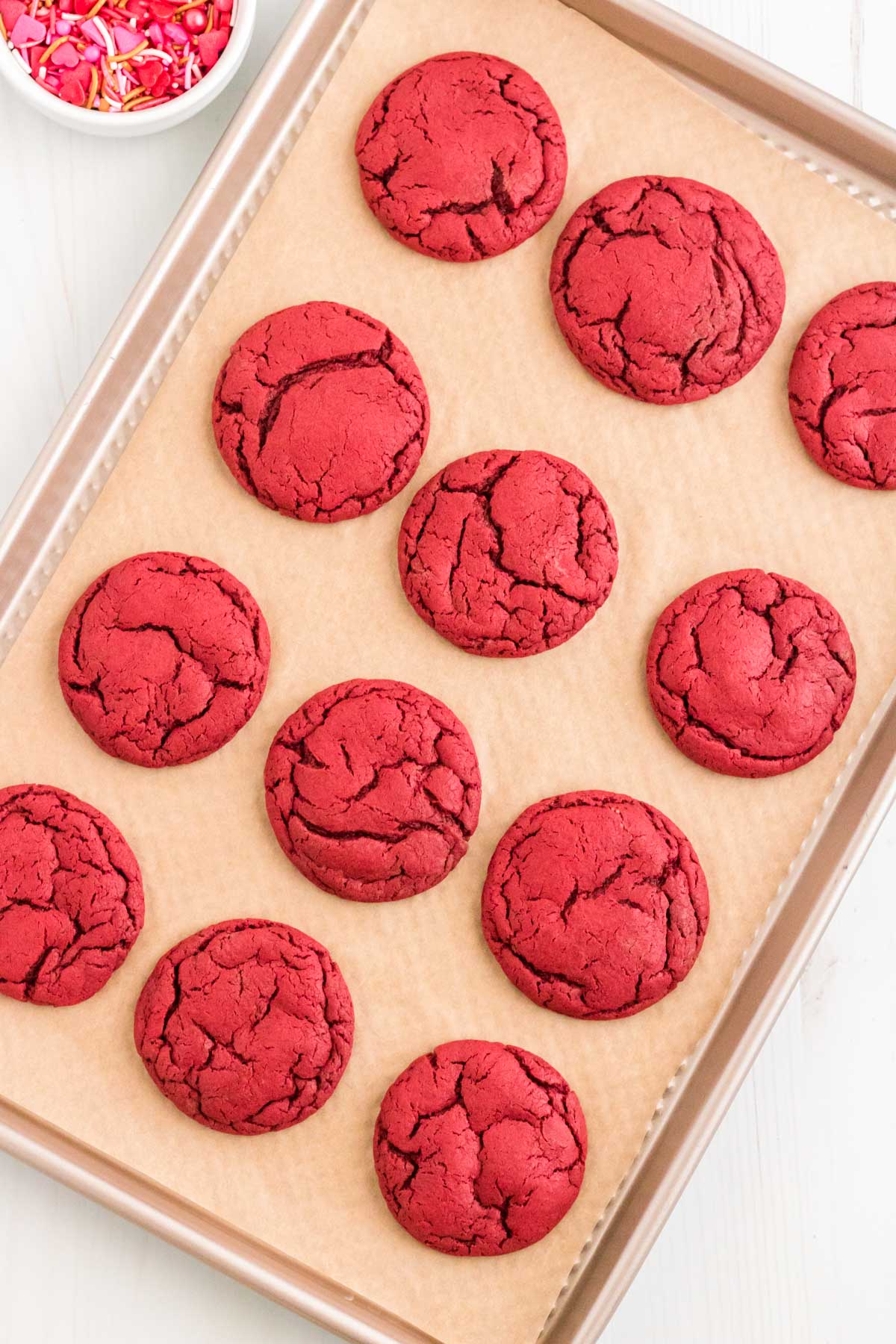 Baked red velvet cookies on a parchment lined baking sheet.