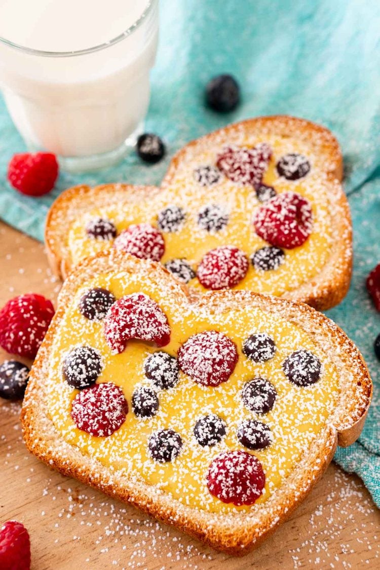 Custard toast on a wooden cutting board dusted with powdered sugar.