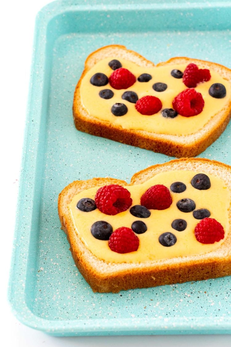 Two slices of yogurt toast ready to be baked on a blue baking sheet.