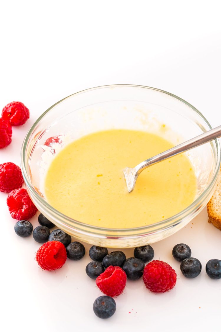 Yogurt toast filling whisked together in a glass mixing bowl with berries around it.