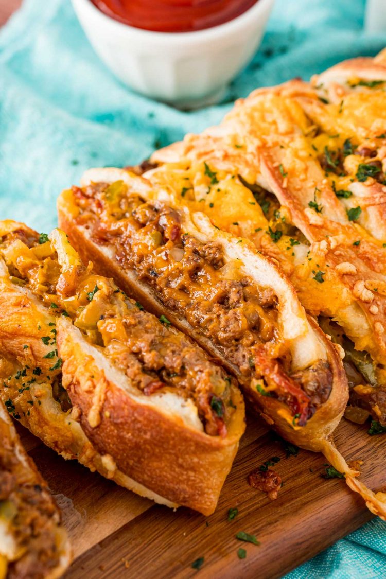 Garbage bread that's been sliced up on a wooden cutting board.