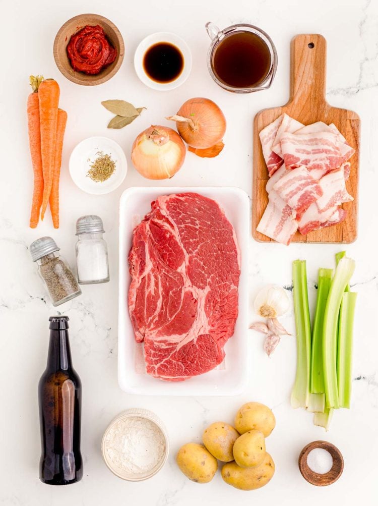 Ingredients to make Irish Beef Stew with Guinness on a white marble table.
