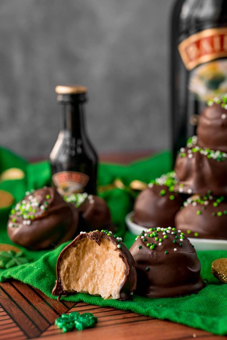 Irish cream truffles on a green napkin, one with a bite taken out of it.