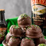 Close up photo of Bailey's Irish Cream Cheesecake Truffles on a white plate on a green napkin.