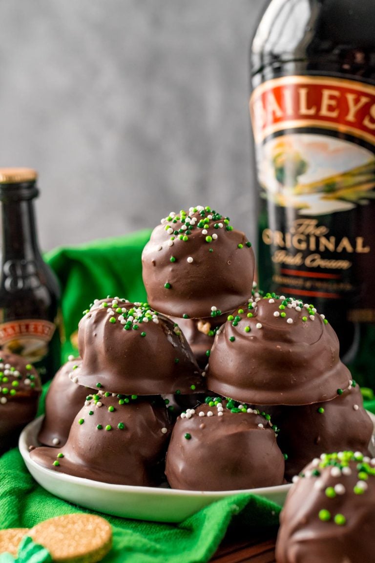 Close up photo of Bailey's Irish Cream Cheesecake Truffles on a white plate on a green napkin.