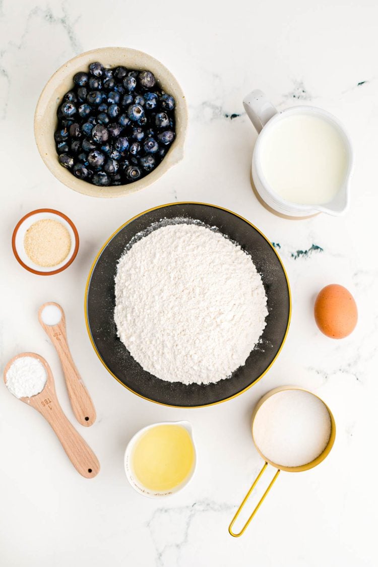 Ingredients to make jumbo blueberry muffins on a marble counter.