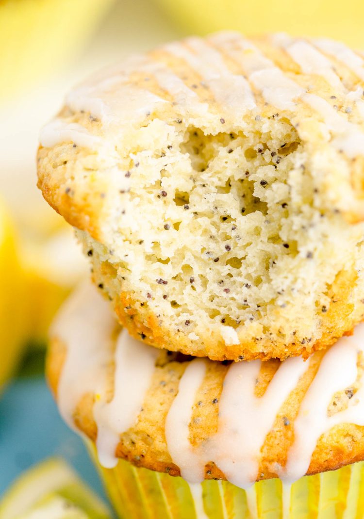 Close up of two lemon muffins stacked on top of each other, the top one is missing a bite.