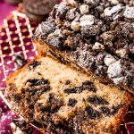 Close up photo of oreo crumb cake on a wire rack partially sliced.