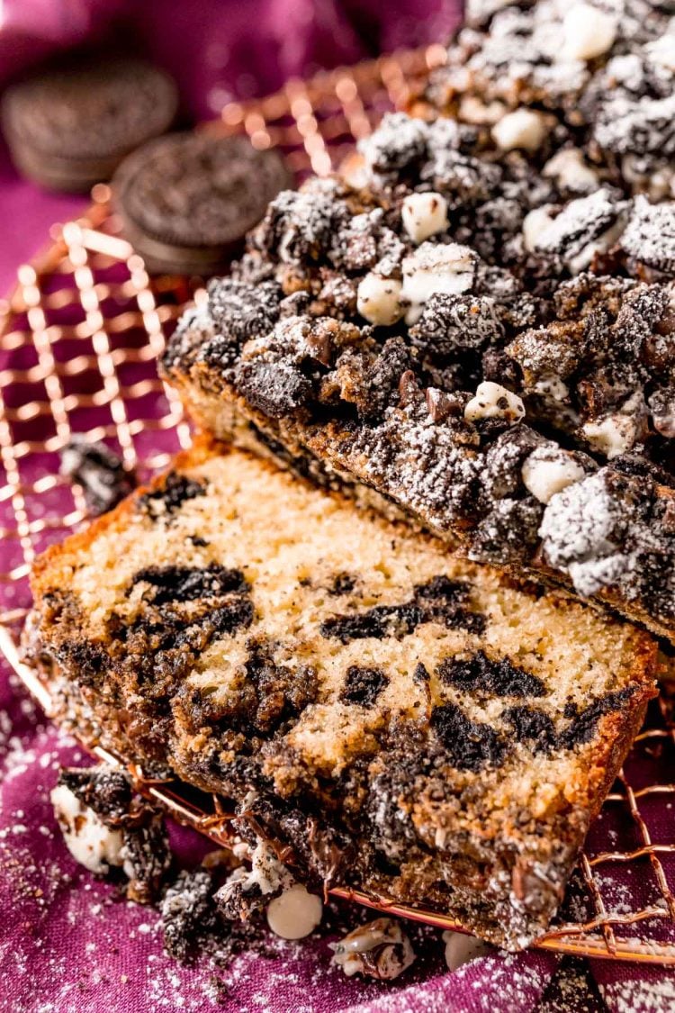 Close up photo of oreo crumb cake on a wire rack partially sliced.