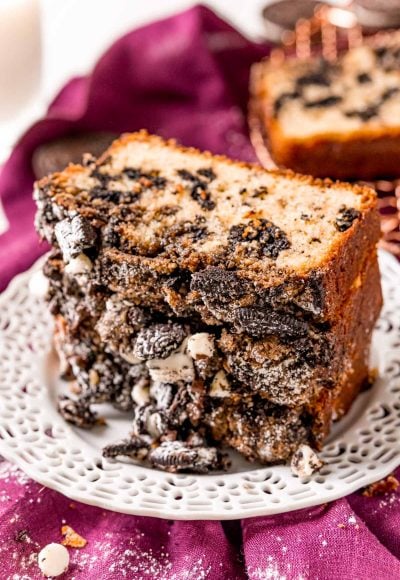 Slices of cookies and cream coffee cake stacked on a white plate on a purple napkin.