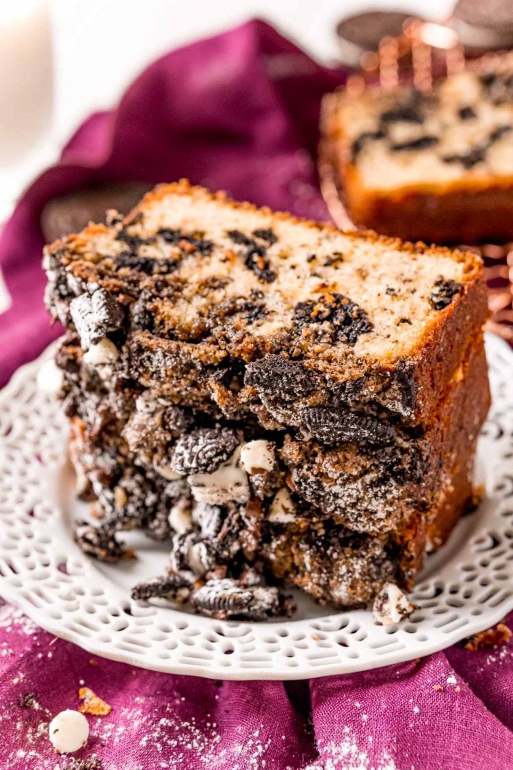 Slices of cookies and cream coffee cake stacked on a white plate on a purple napkin.