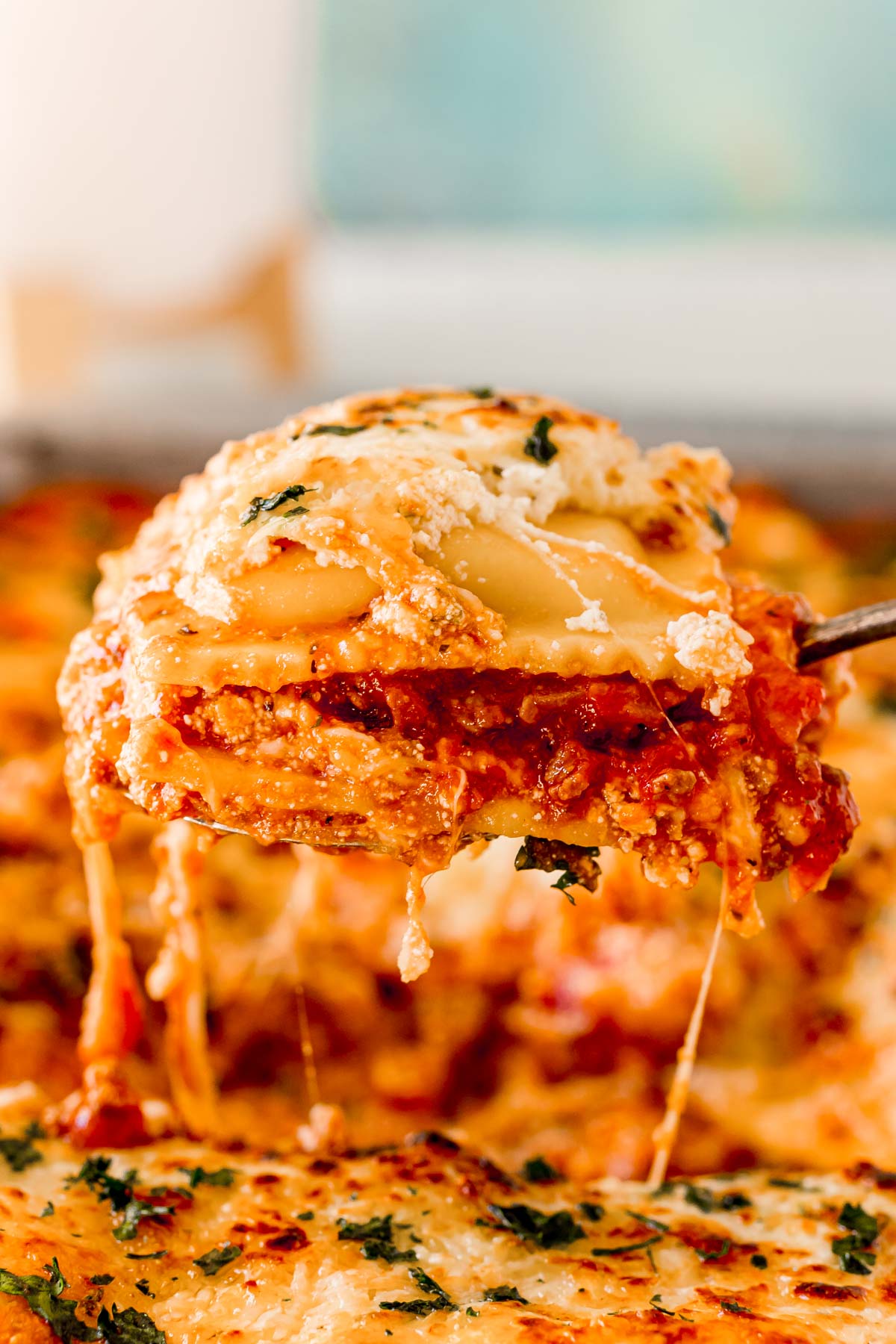 Ravioli lasagna being scooped out of a pan.