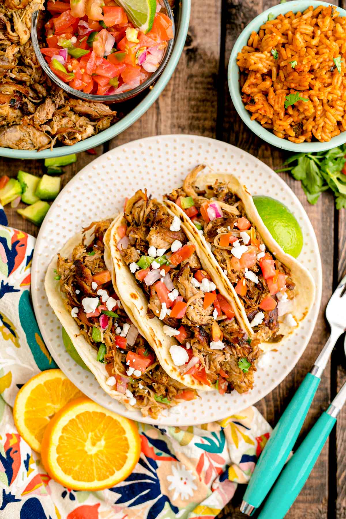 Close up photo of pork carnita tacos on a white plate.