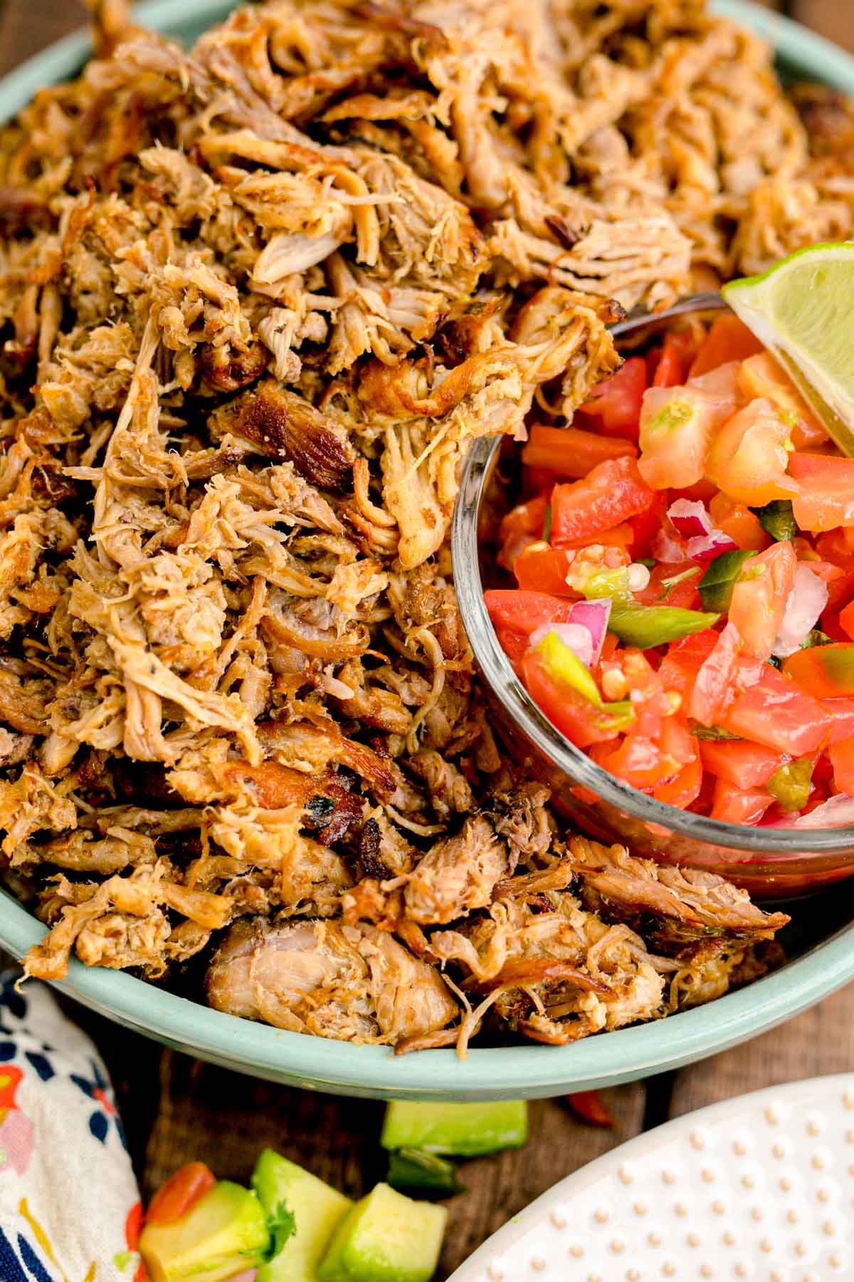 Pork carnitas in a teal bowl with pico de gallo.