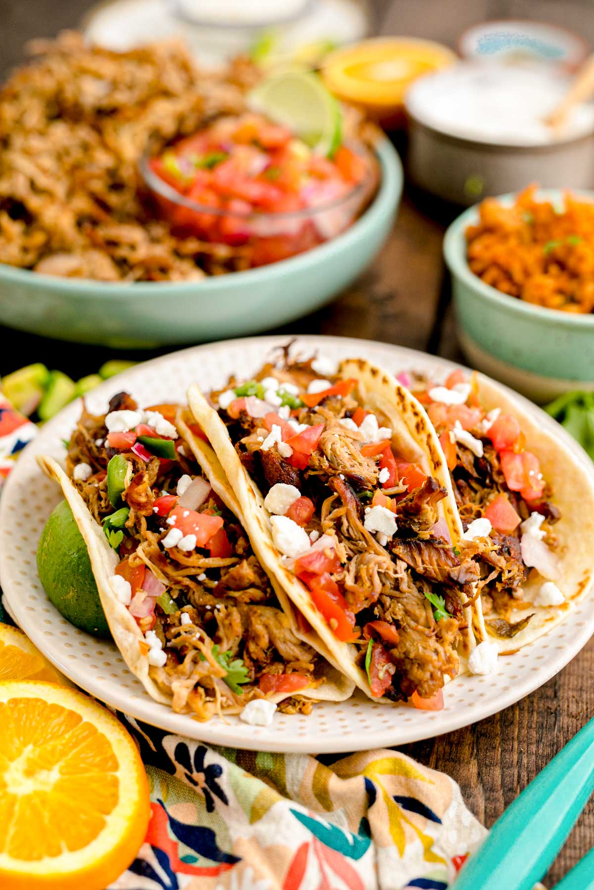 Close up photo of pork carnita tacos on a white plate.