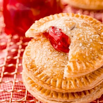 Close up photo of cherry hand pies on a copper wire rack.