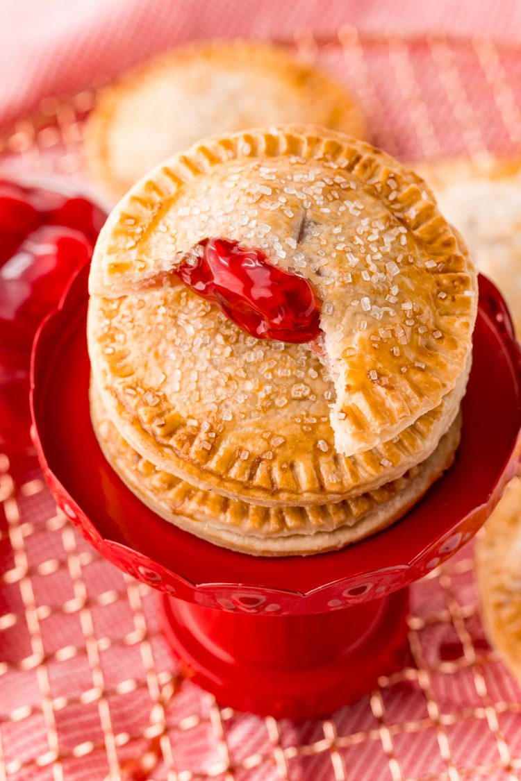 Cherry hand pies stacked on a small dessert stand.