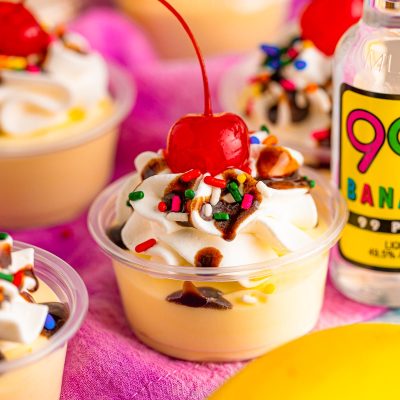 Close up photo of banana split pudding shots in plastic shot containers.