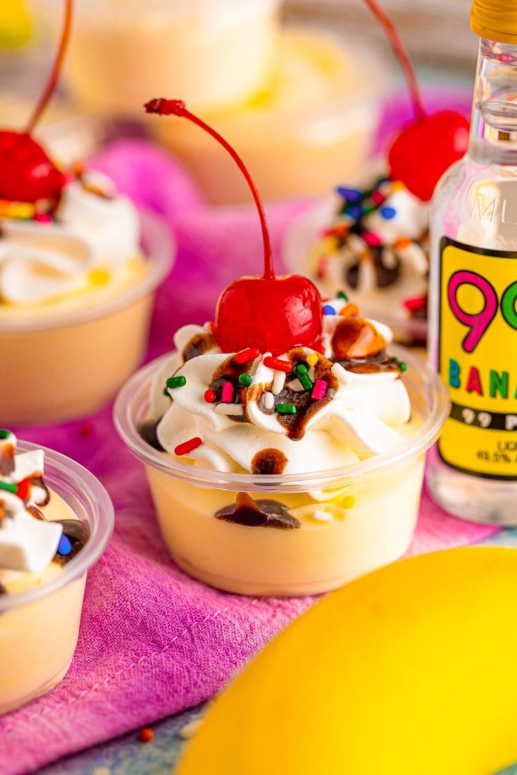 Close up photo of banana split pudding shots in plastic shot containers.