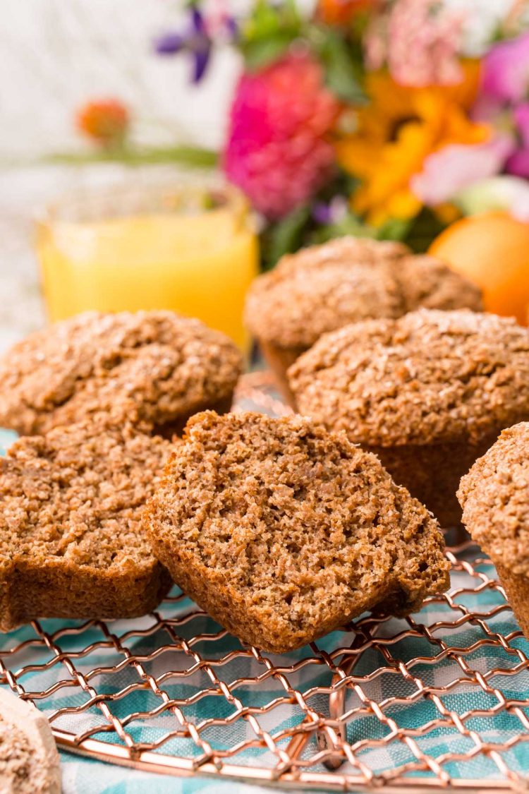 A bran muffin sliced in half on a copper wire rack.