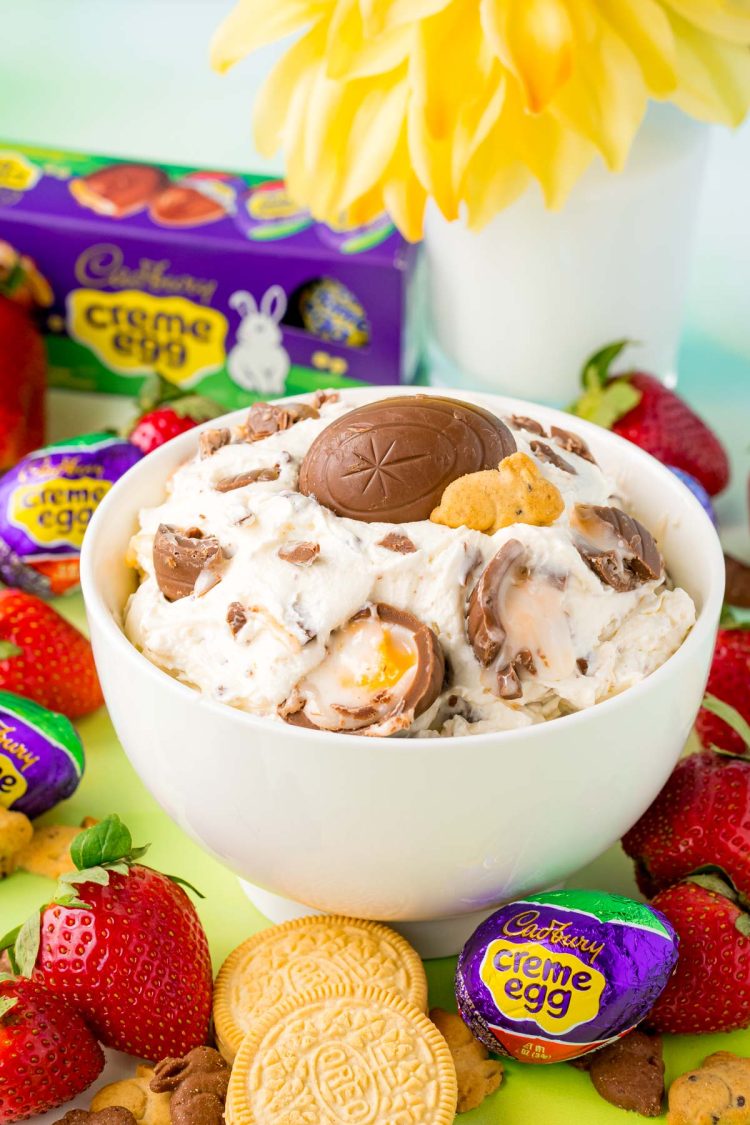A white bowl with cadbury creme egg dip in it with strawberries around it.