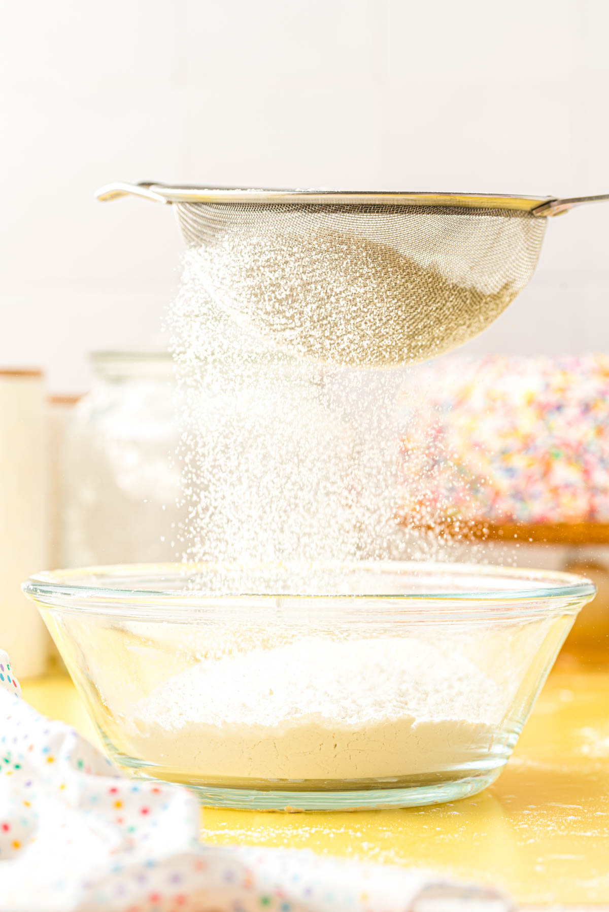 Flour being sifted through a fine mesh sieve.