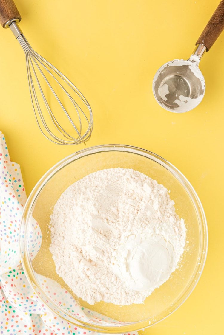 Flour and cornstarch being mixed together in a glass mixing bowl.