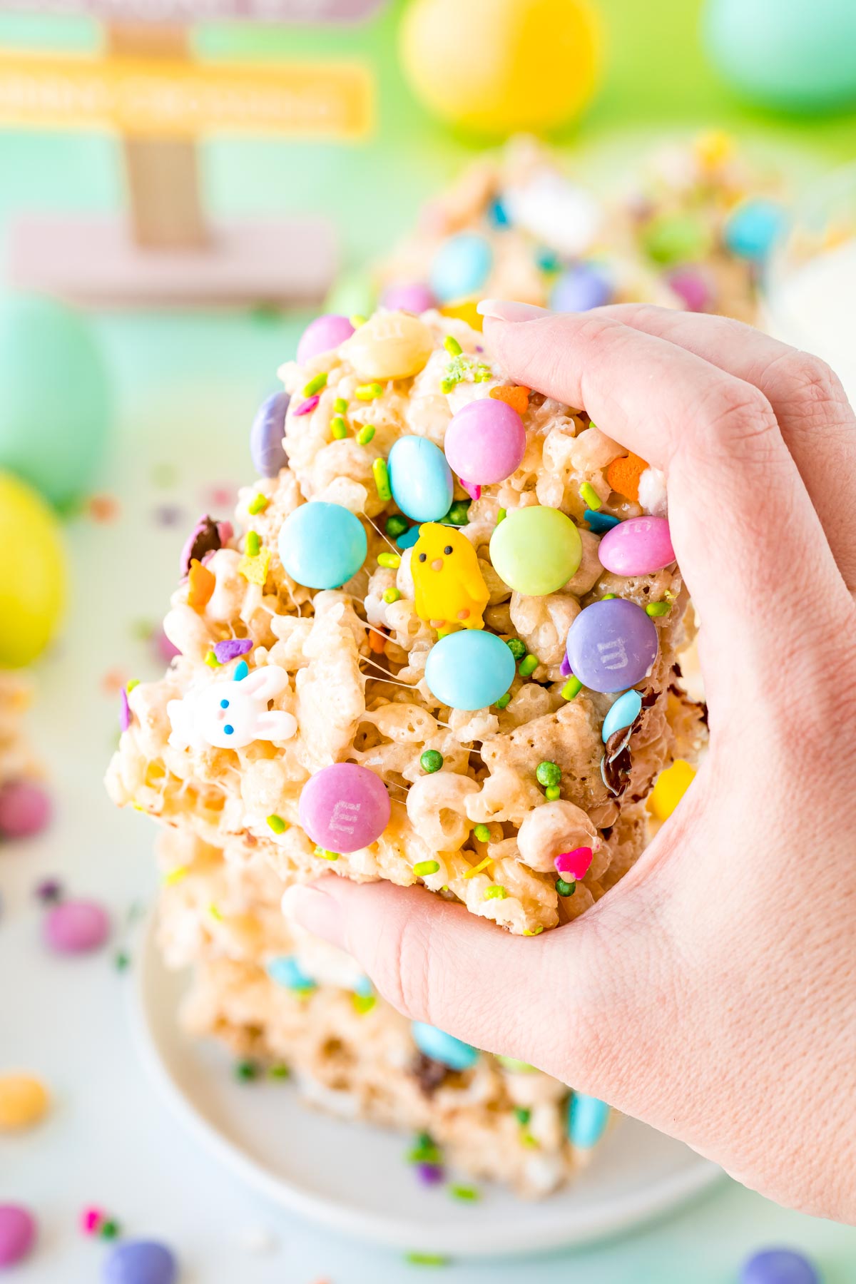 A woman's hand holding a Easter rice krispie treat to the camera.