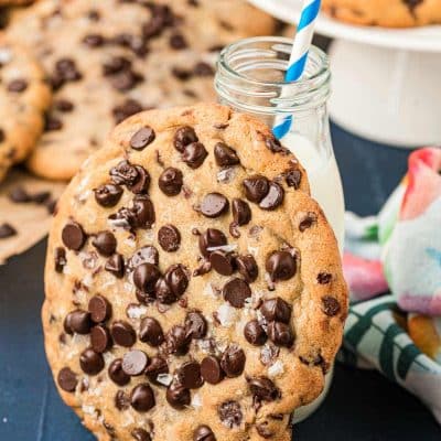 Giant chocolate chip cookie leaning against a bottle of milk.
