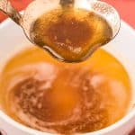 Brown butter being ladled out of a bowl.