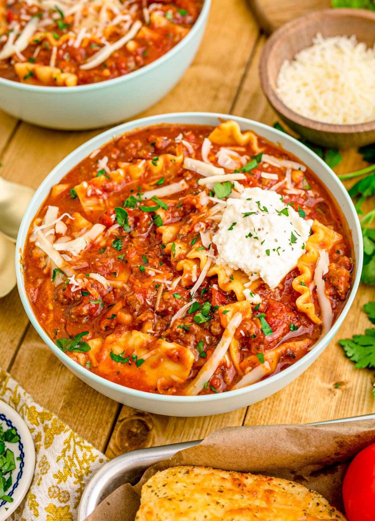 A bowl of lasagna soup on a wooden table.