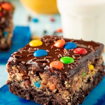 Close up of a slice of monster cookie dough brownies on a blue coaster.