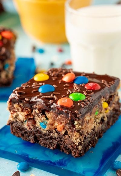 Close up of a slice of monster cookie dough brownies on a blue coaster.