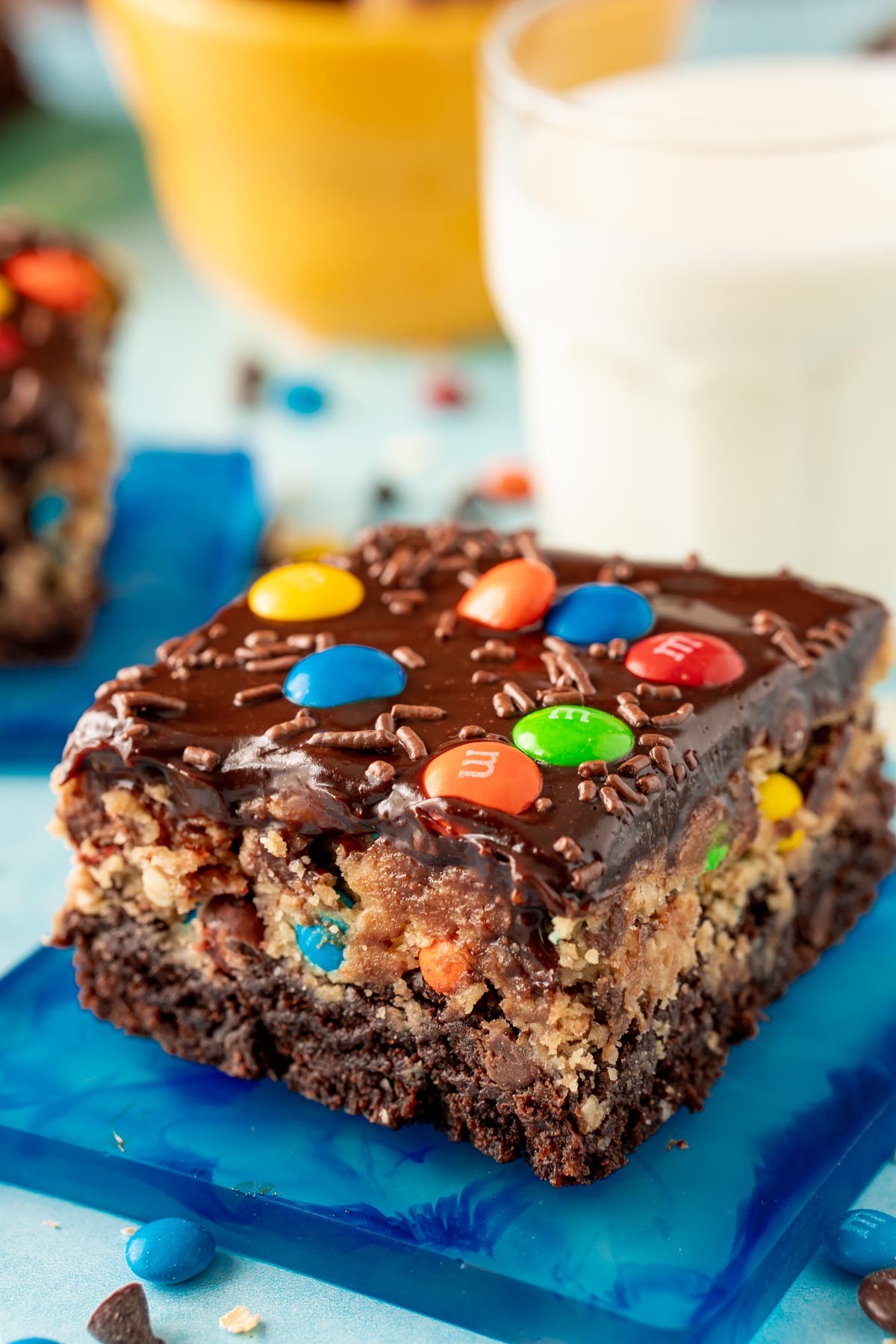 Close up of a slice of monster cookie dough brownies on a blue coaster.