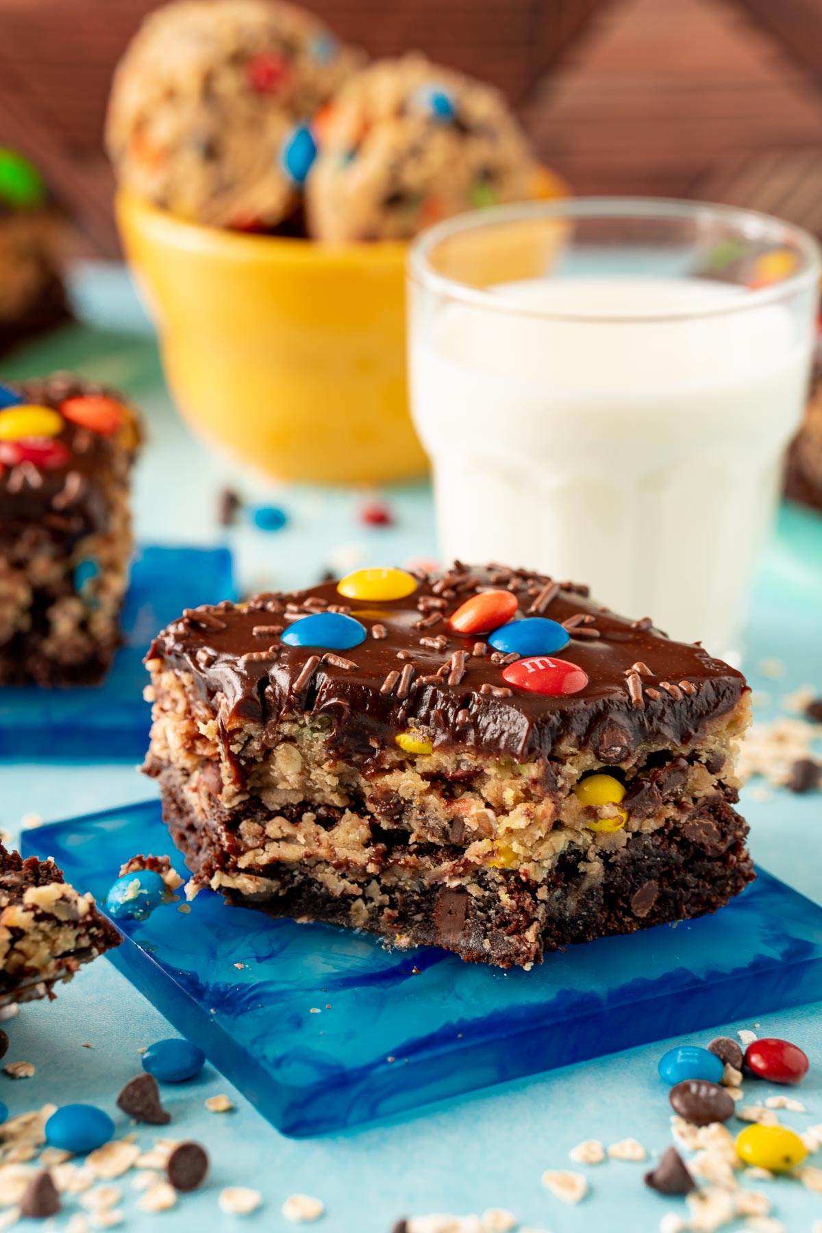 A monster cookie dough brownie on a blue coaster with a bite taken out of it.