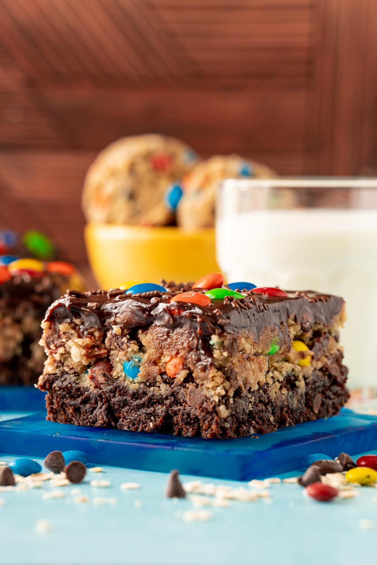 Close up of a slice of monster cookie dough brownies on a blue coaster.