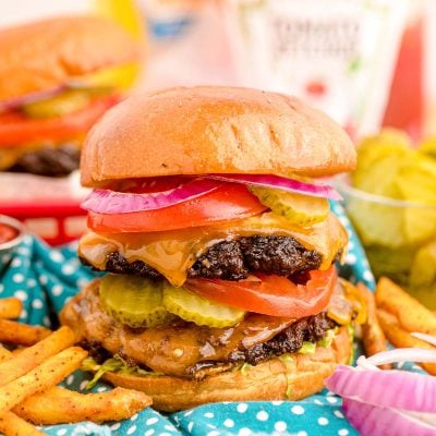 Close up of a smash burger on a blue napkin with condiment bottles in the background.