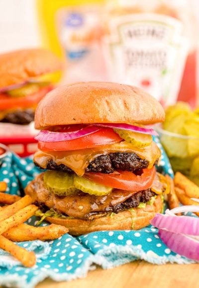 Close up of a smash burger on a blue napkin with condiment bottles in the background.
