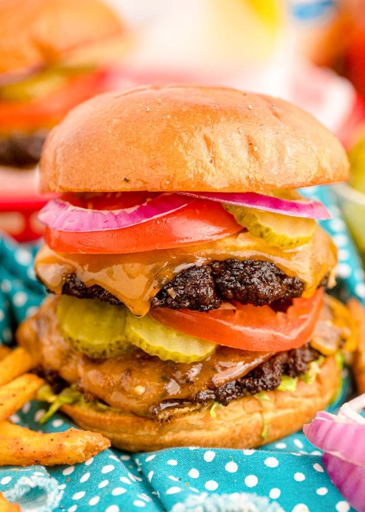 Close up of a smash burger topped with pickles, tomatoes, onions, and more.