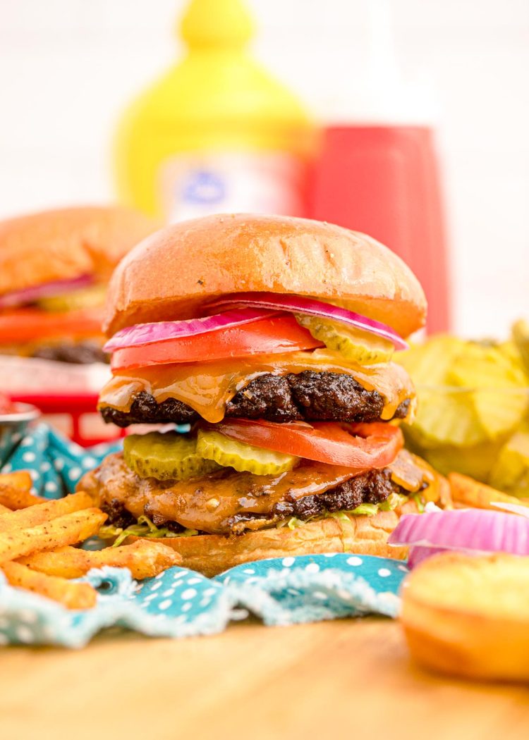 Close up of a smash burger on a blue napkin with condiment bottles in the background.