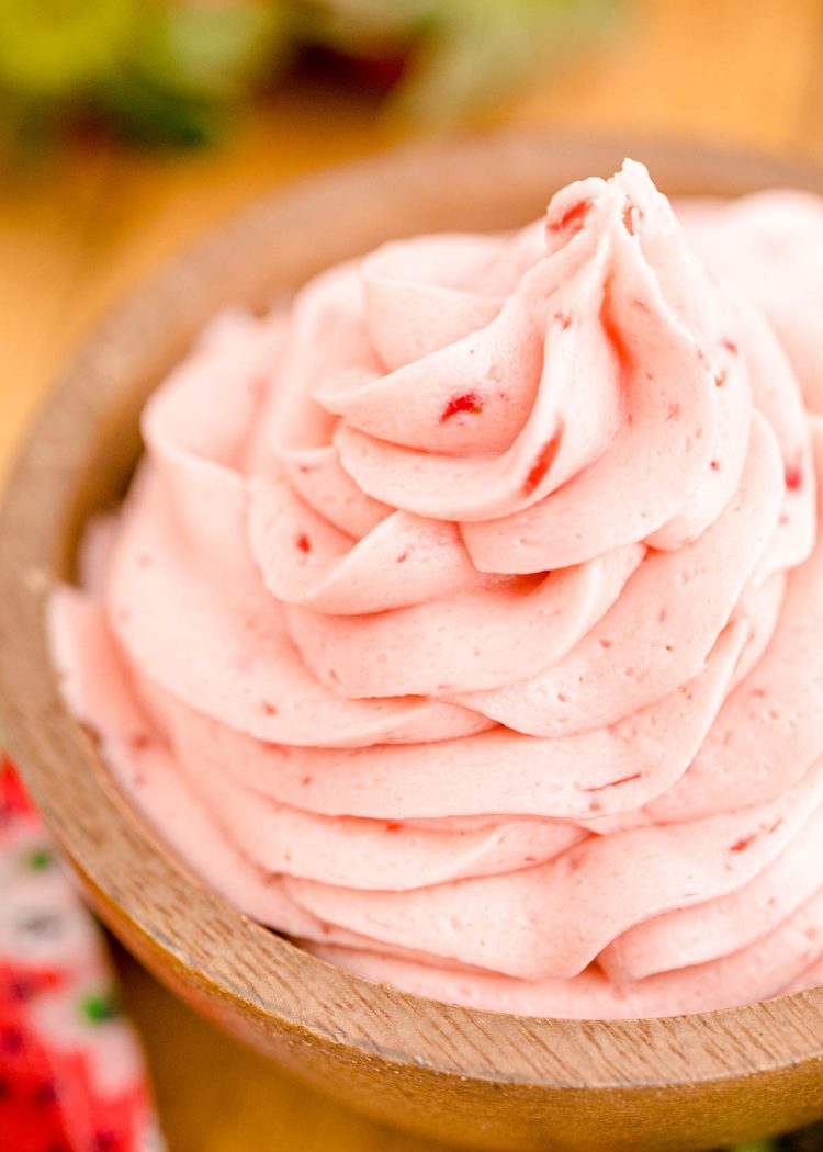 Close up of strawberry buttercream frosting in a wooden bowl.