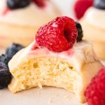 Shortcake Cookies topped with frosting and berries with a bite taken out of it.