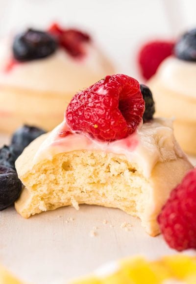 Shortcake Cookies topped with frosting and berries with a bite taken out of it.