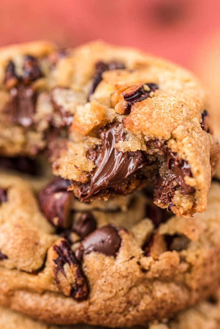 Close up of pecan chocolate chip cookies stacked with one bitten into.