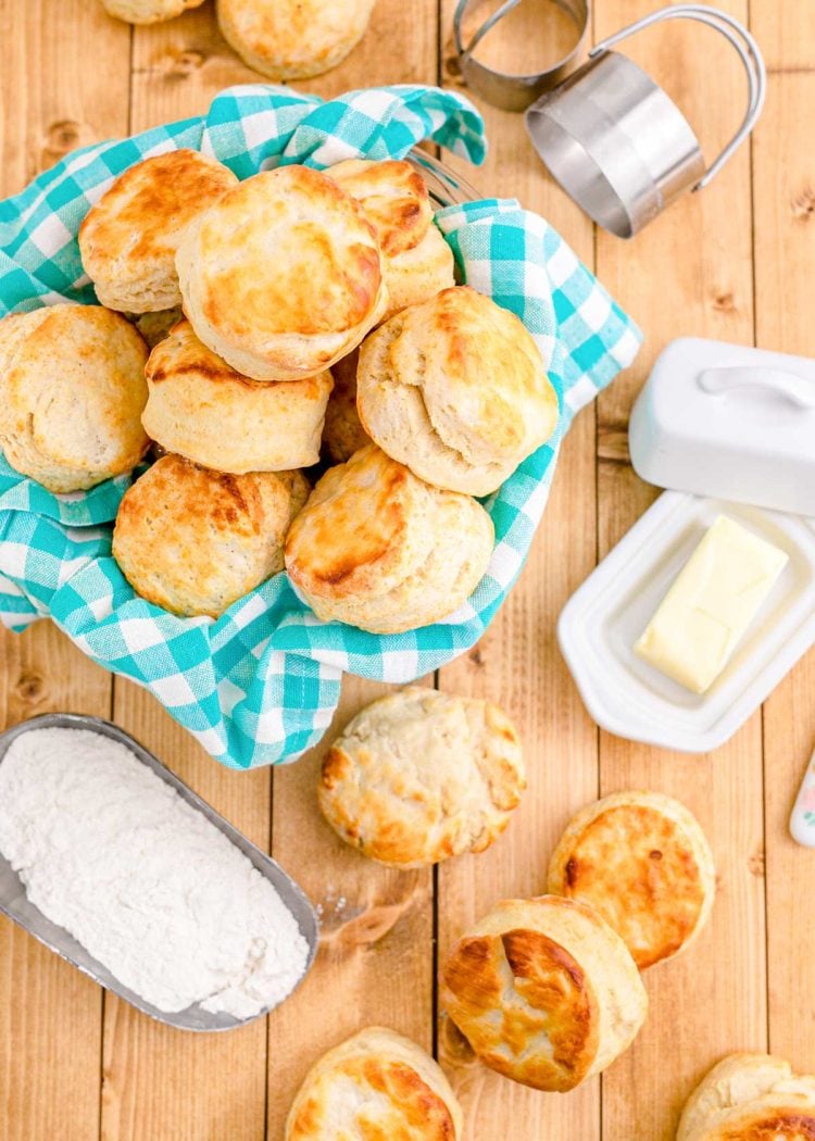 Buttermilk biscuits in a basket with a teal napkin and on a wooden table.