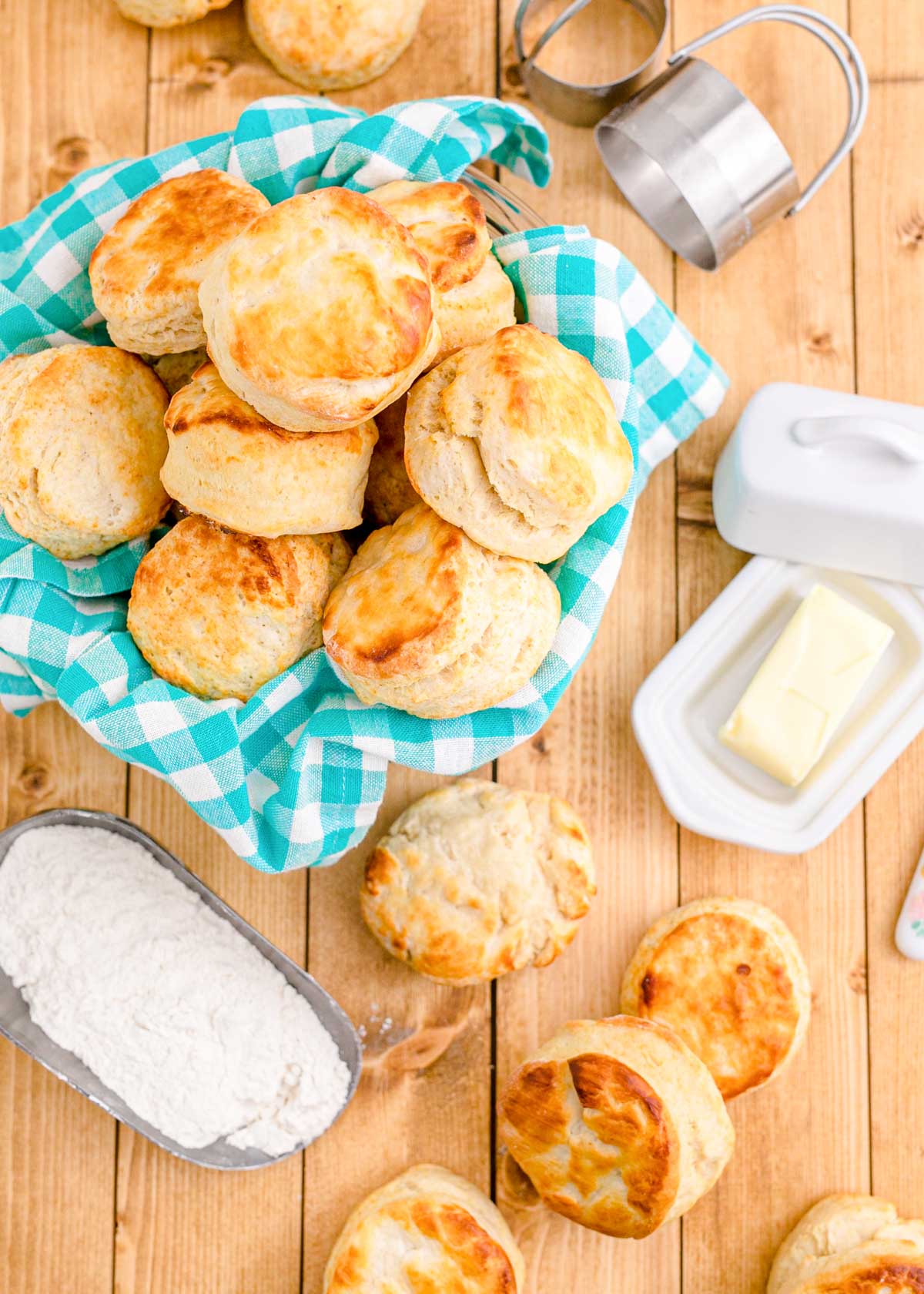Buttermilk biscuits in a basket with a teal napkin and on a wooden table.