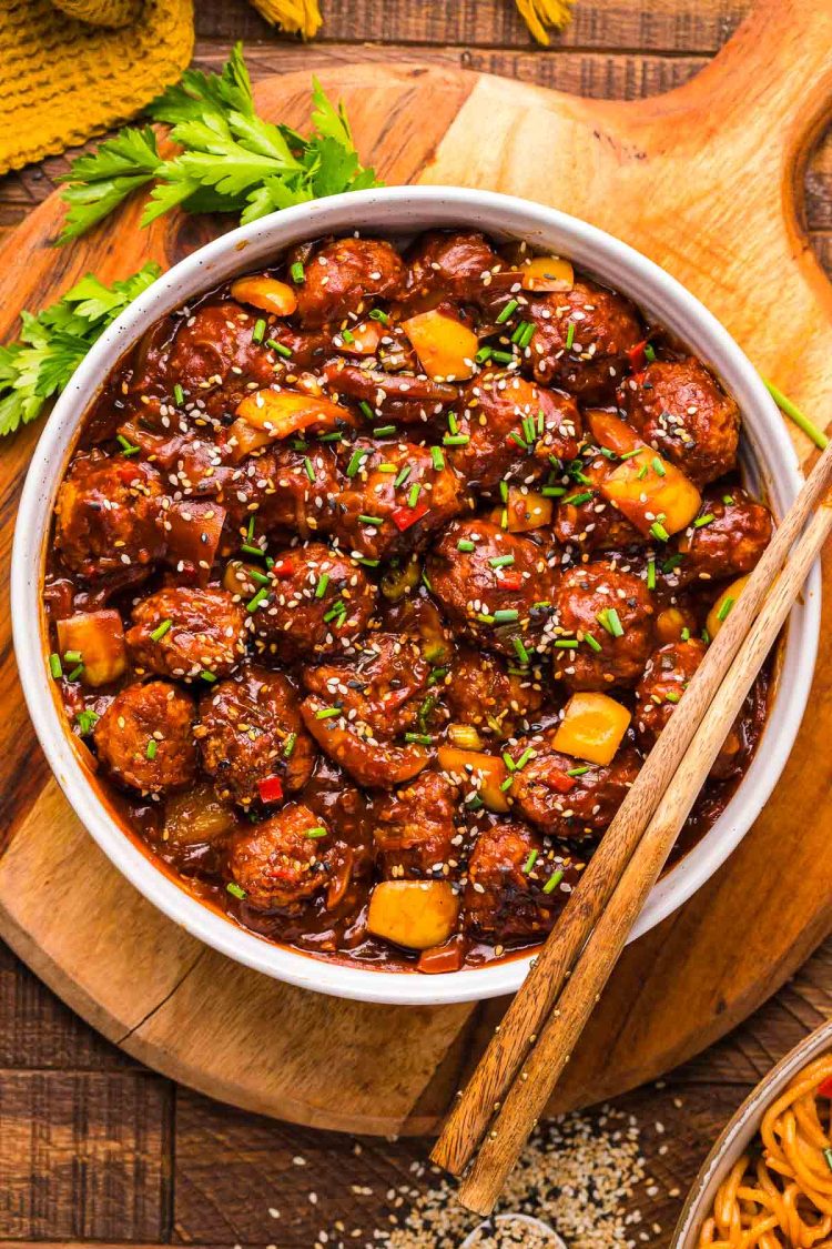 Overhead photo of a bowl of chicken manchurian with chop sticks resting on the bowl.