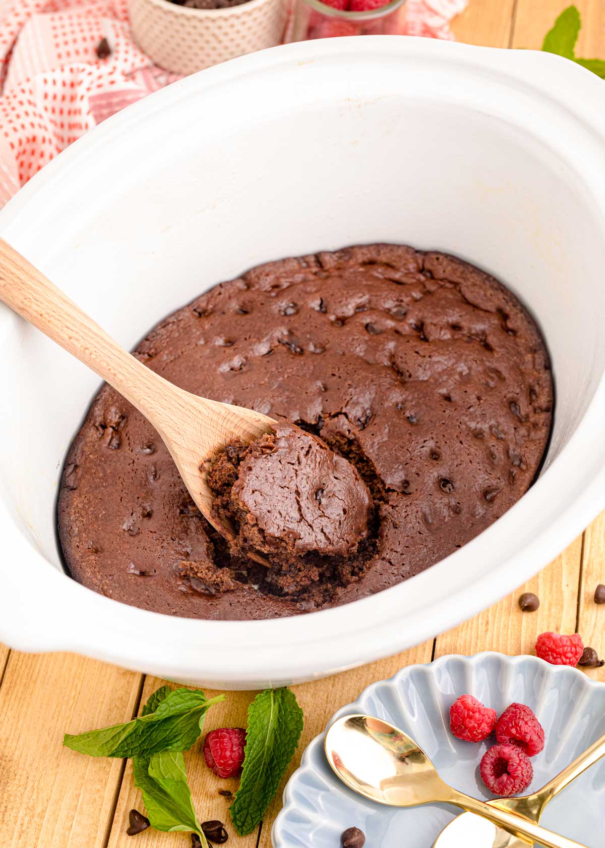 Chocolate cake being scooped out of a white crockpot.